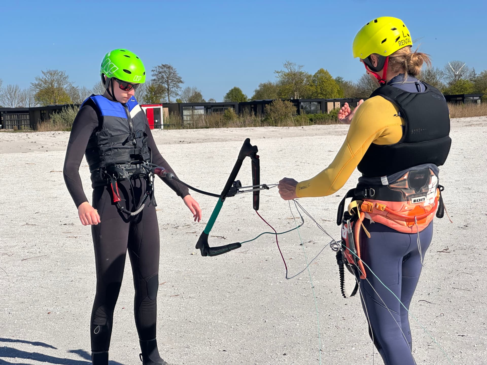 Instructor candidate handing the control bar to a student on the beach