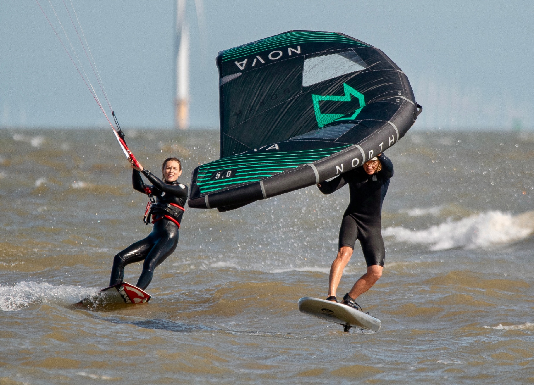 Coach guiding a rider with a wing on the water