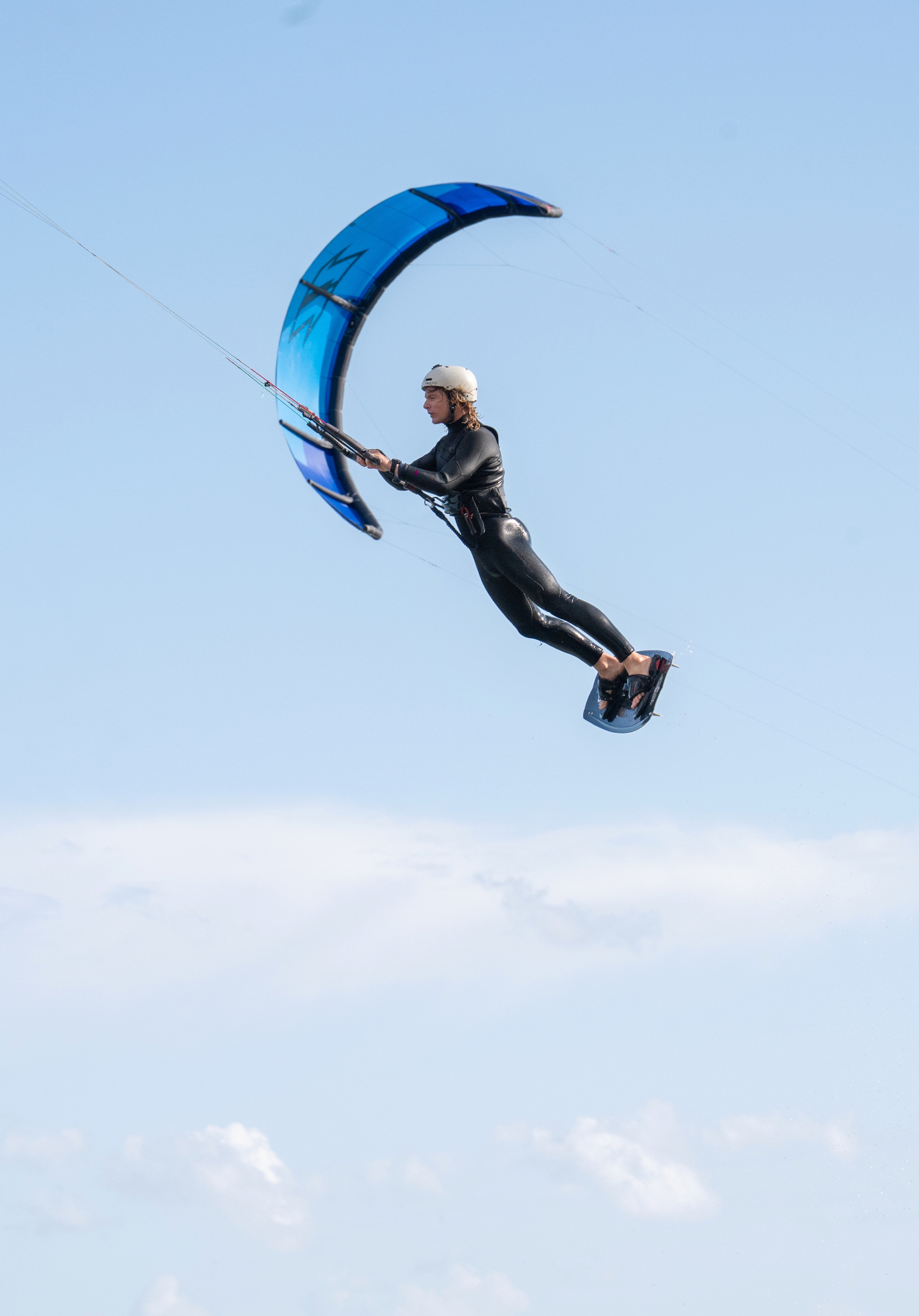 Kitesurfer airborne against a blue sky at Martello Bay, Essex